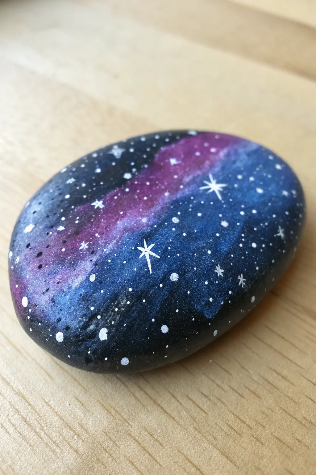 Mini galaxy rock painting with deep purples and blues, glowing nebula swirls, and starry speckles