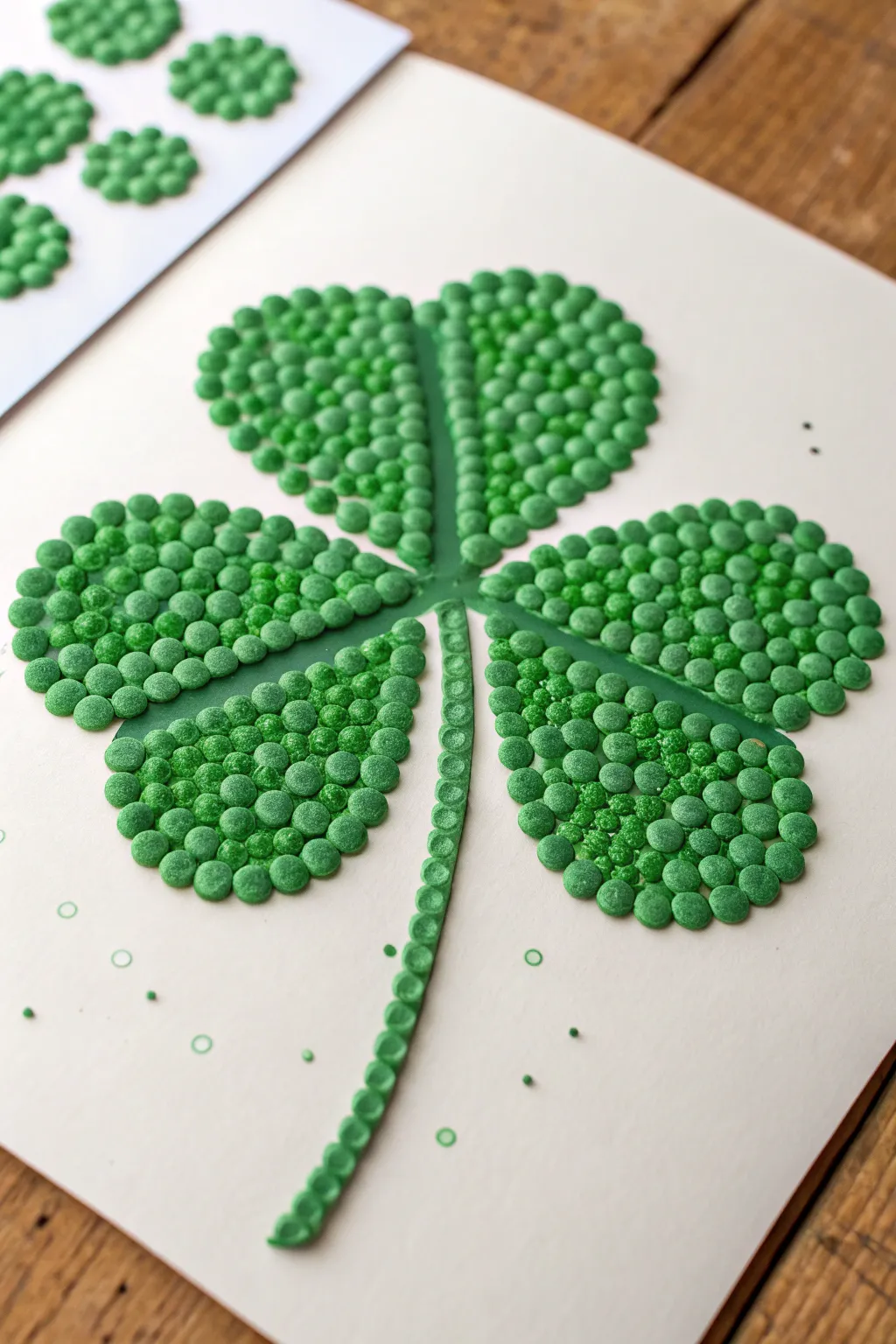 Four leaf clover in green puffy paint dot clusters, crisp contrast and satisfying bumpy texture