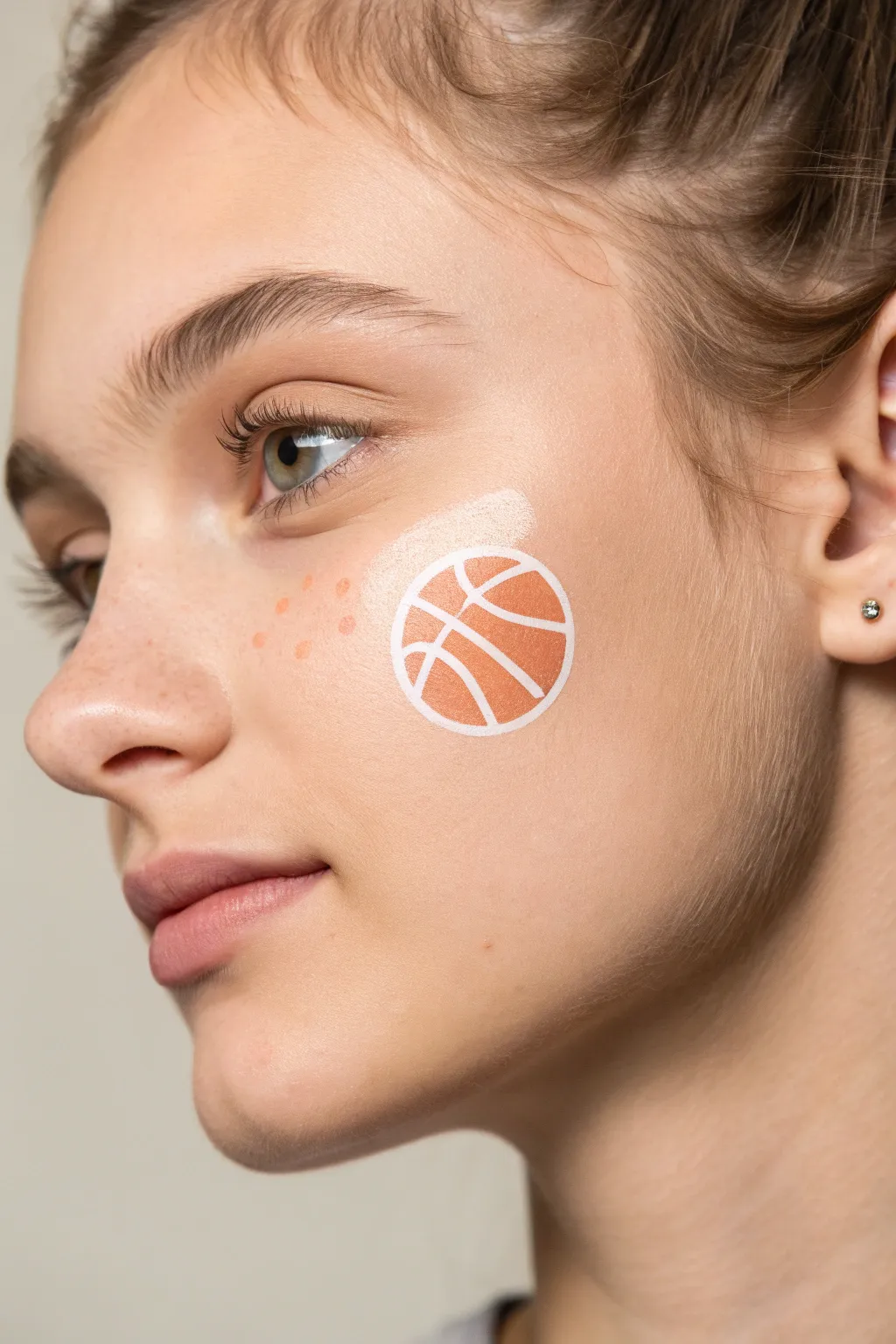 Tiny sports ball cheek icon in a minimalist palette, a quick face paint idea with clean contrast