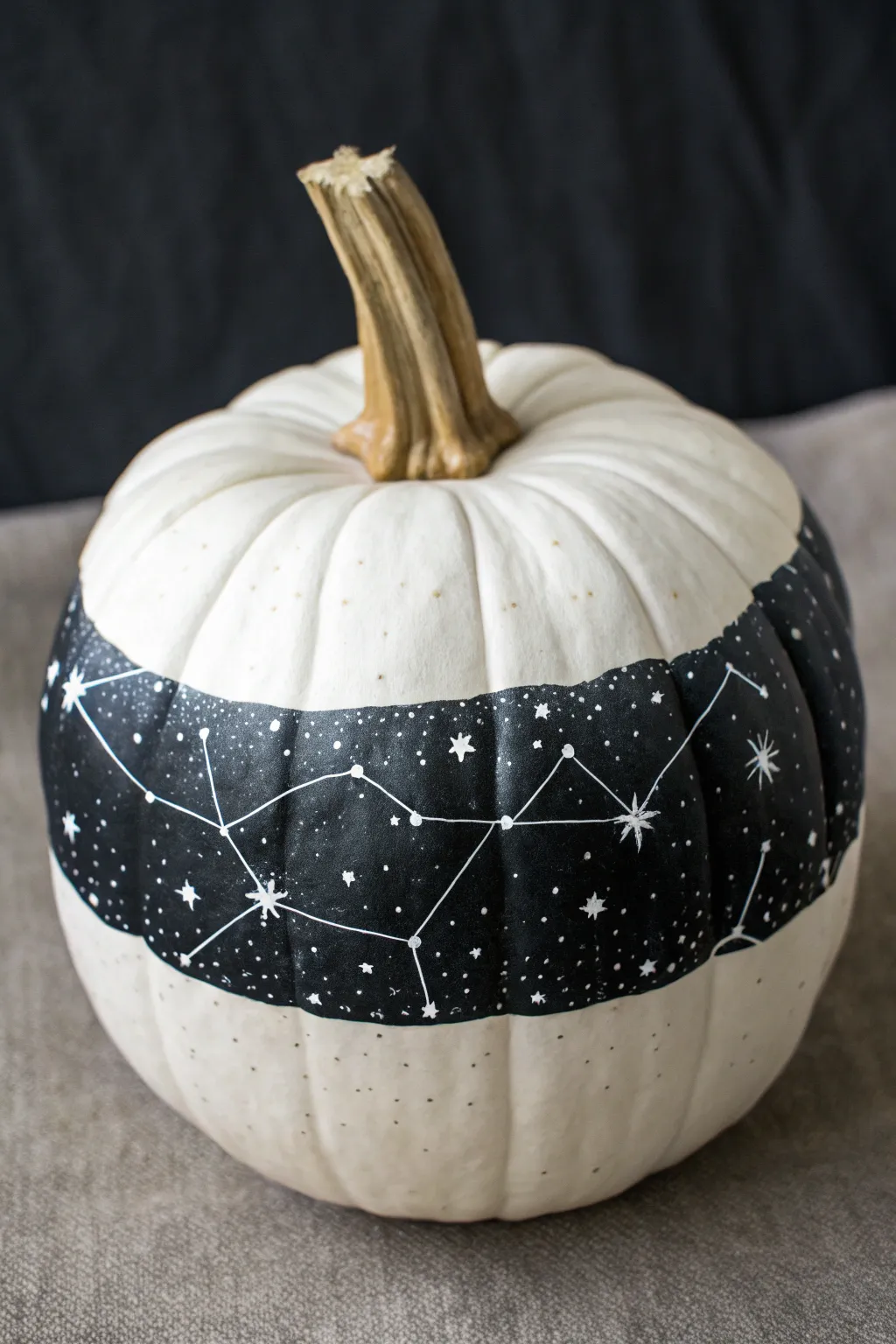 Celestial constellation design on a white pumpkin, minimalist boho drama with crisp contrast.