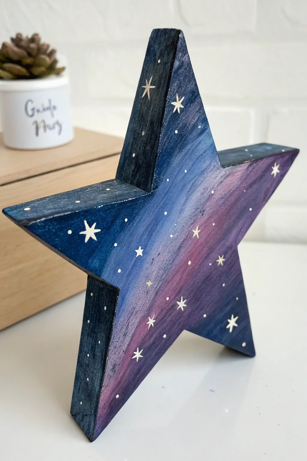Galaxy night-sky wooden star with splatter stars and glowing nebula accents in deep indigo hues.