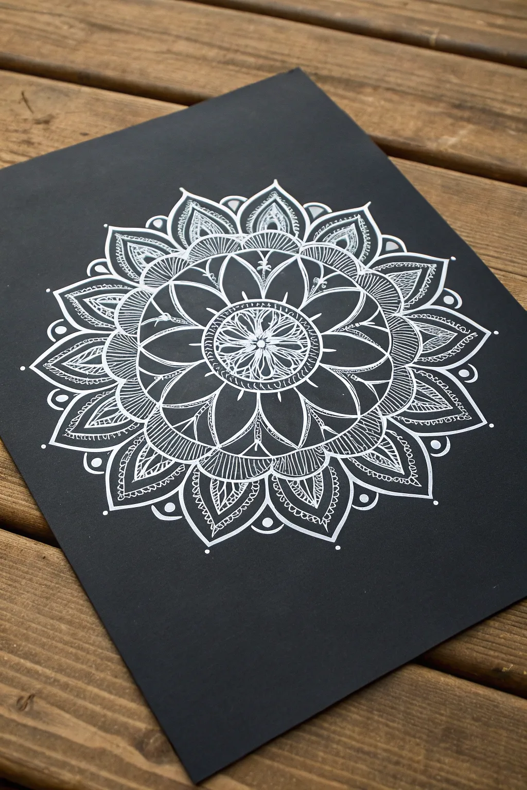 Crisp white chalk mandala on matte black, letting negative space create calming symmetry
