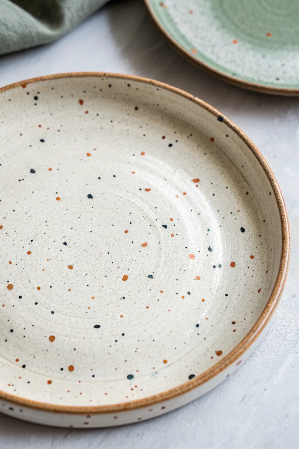 Speckled terrazzo plate close-up with simple three-color marks that feel easy to copy