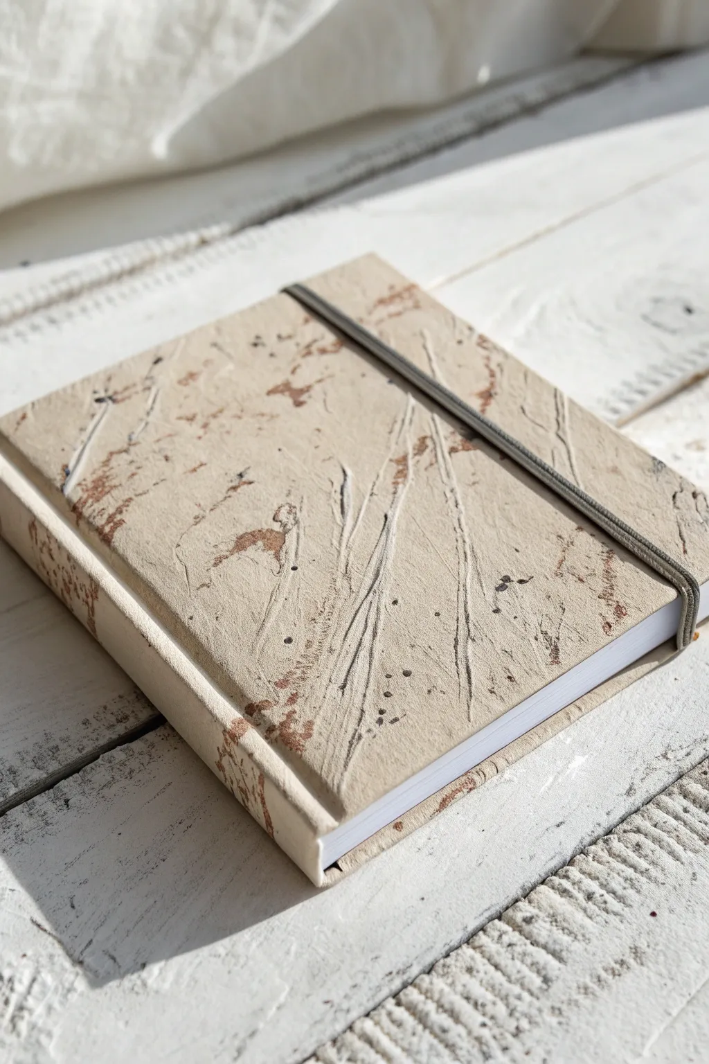 Textured mixed-media sketchbook cover with minimalist ink marks, softly lit to highlight depth