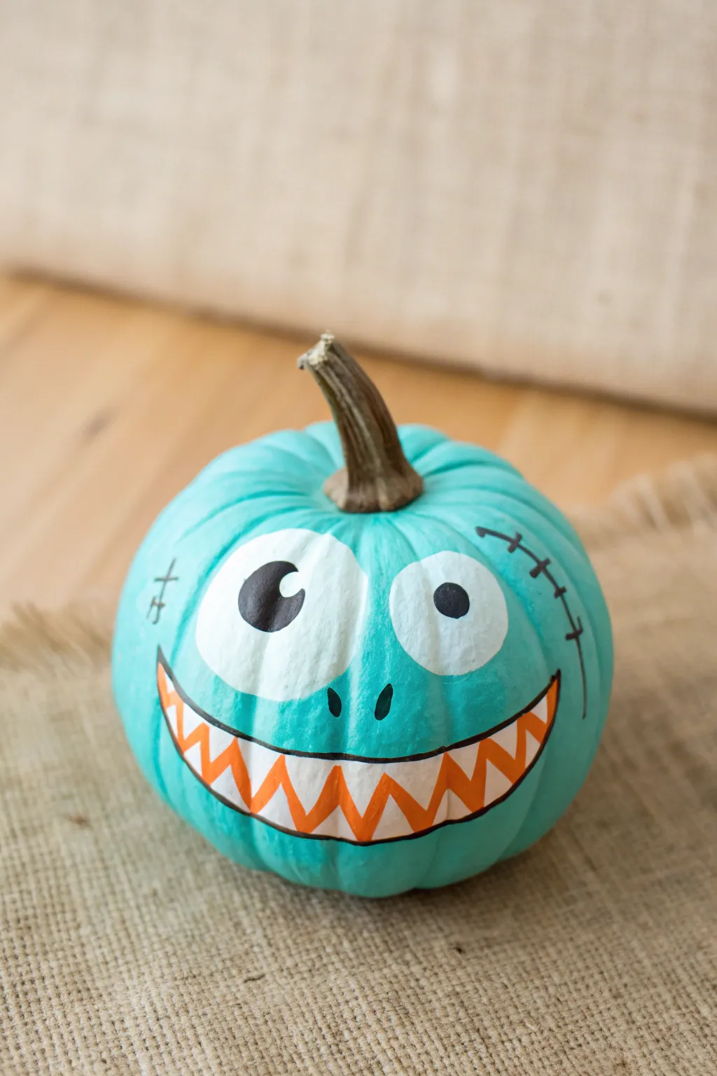 One-eyed monster mini pumpkin with clean lines and bold color on a calm Scandinavian backdrop