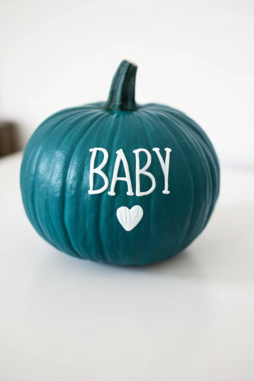 Mini pumpkin painted in rich teal with bold script name and tiny heart, Scandi boho vibes.