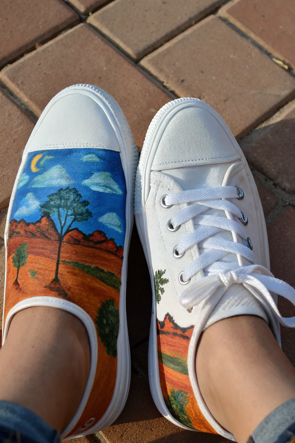 One landscape mural flows across both canvas shoes, bold colors on a clean minimalist backdrop.
