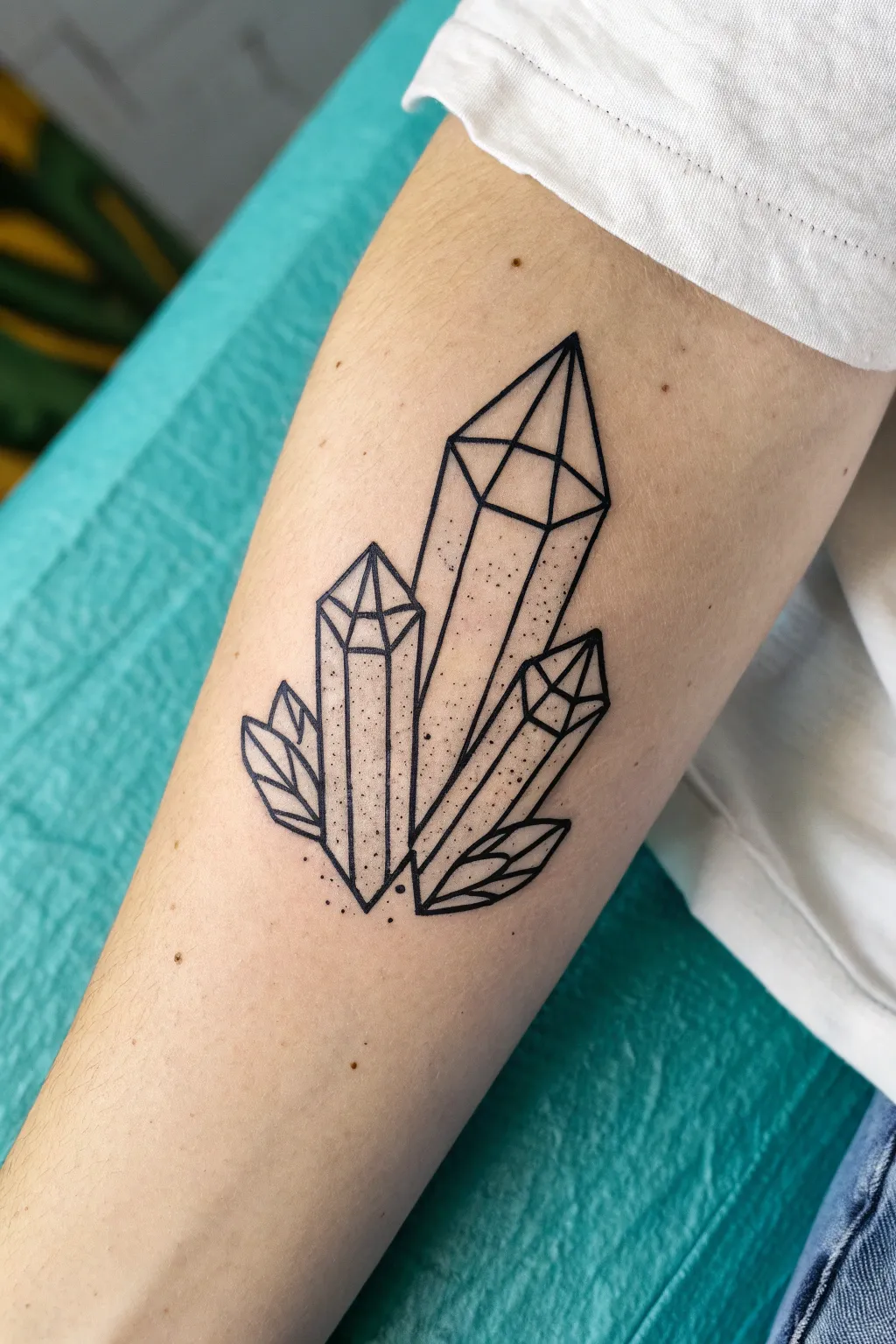 Minimal crystal stack line art tattoo idea with geometric facets, clean, bold, and feminine.