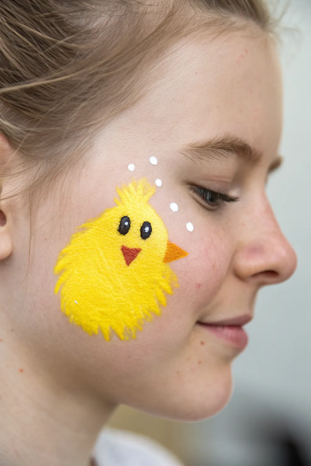 Fluffy chick cheek paint with soft sponged edges, bold yellow contrast, minimal and Easter-cute