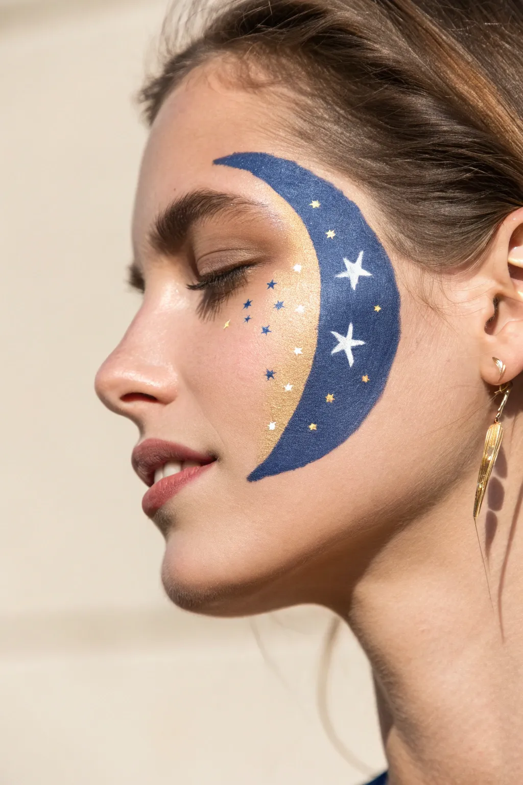 Crescent moon cheek paint with tiny stars and stardust dots for a simple dreamy look