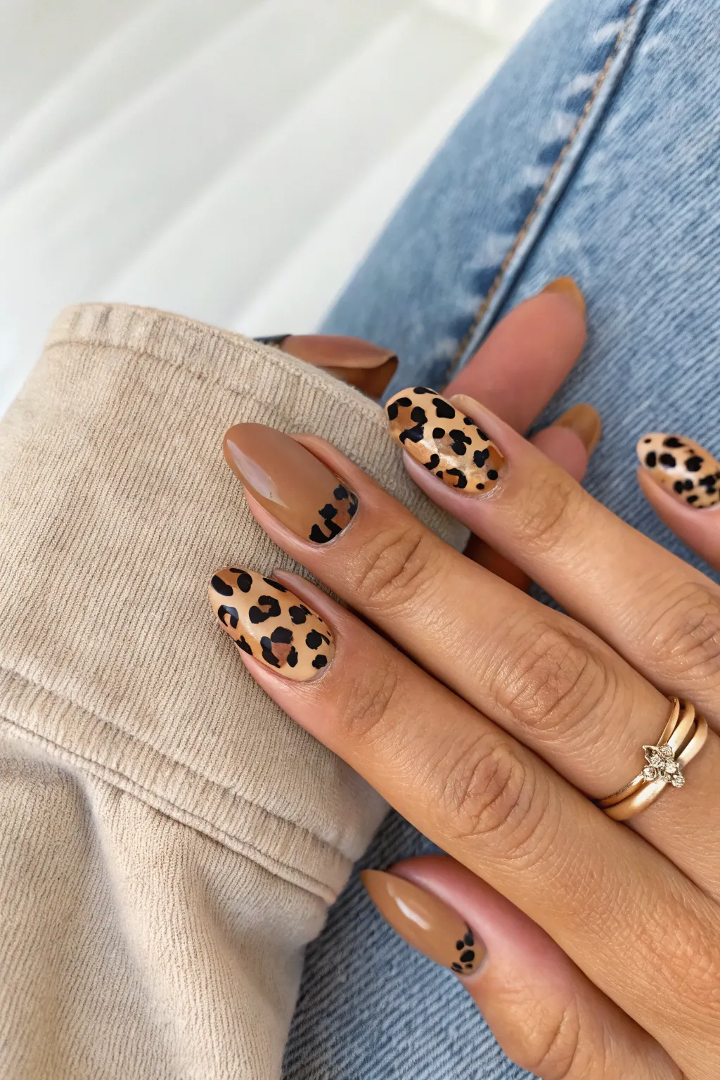 Classic leopard spot manicure: neutral base, brown-black accents, and cozy solid shades.