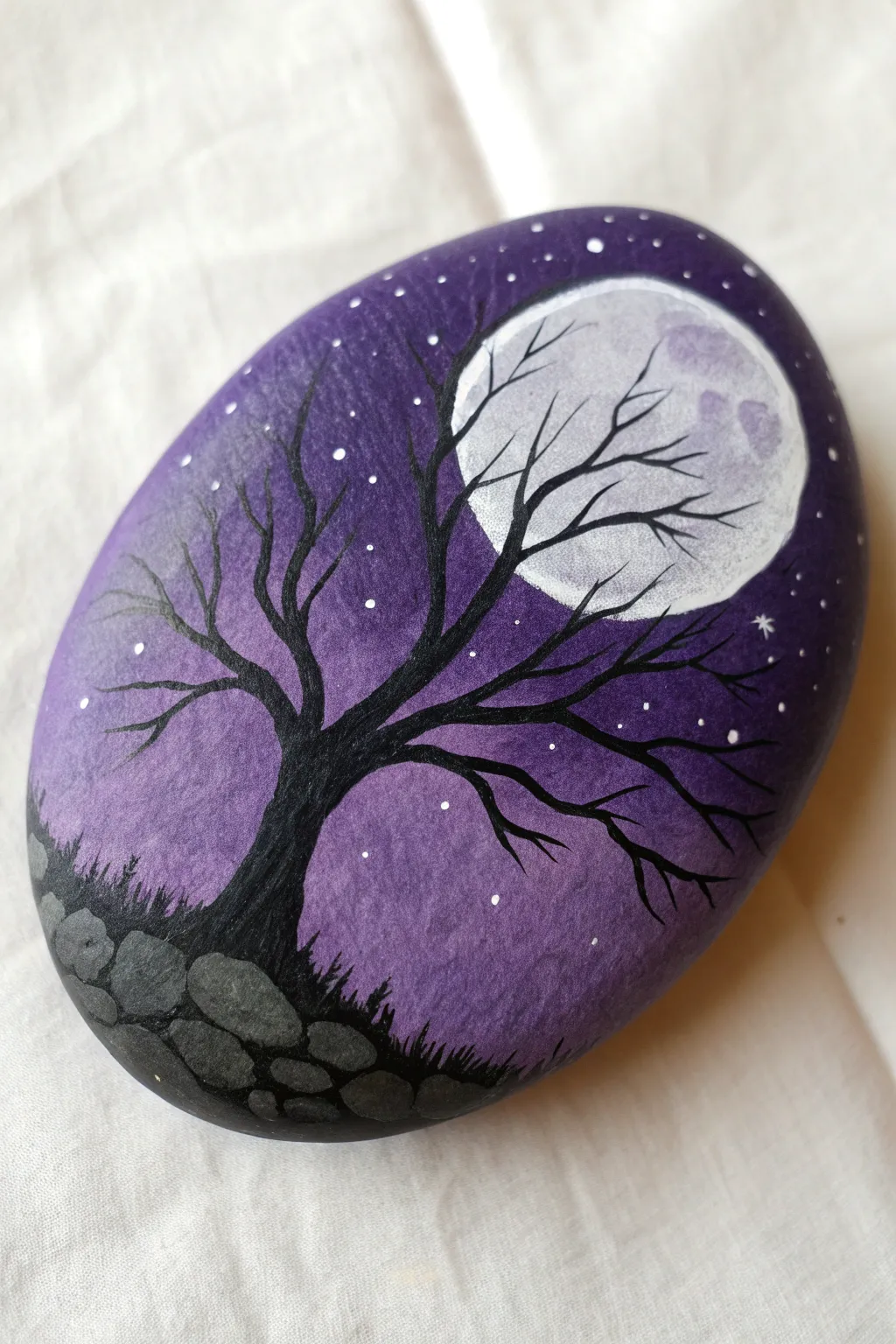 Purple full moon rock painting with spindly black trees, minimalist night-sky magic in one stone