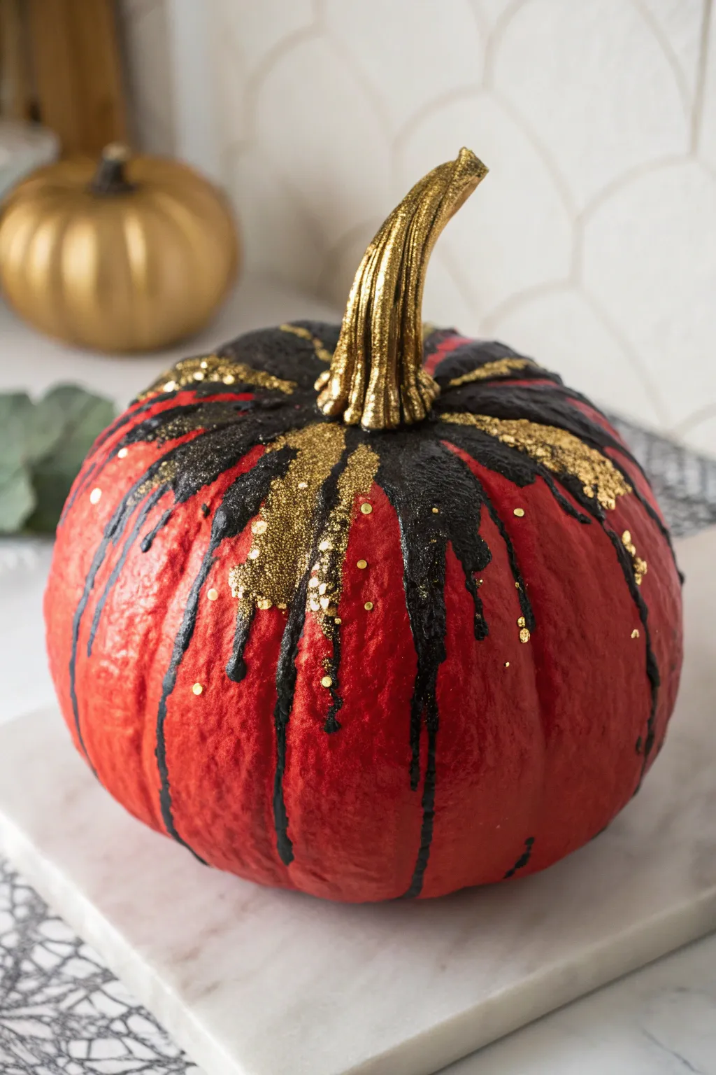 Red pumpkin with black and gold glitter drips, sparkling under soft directional light.