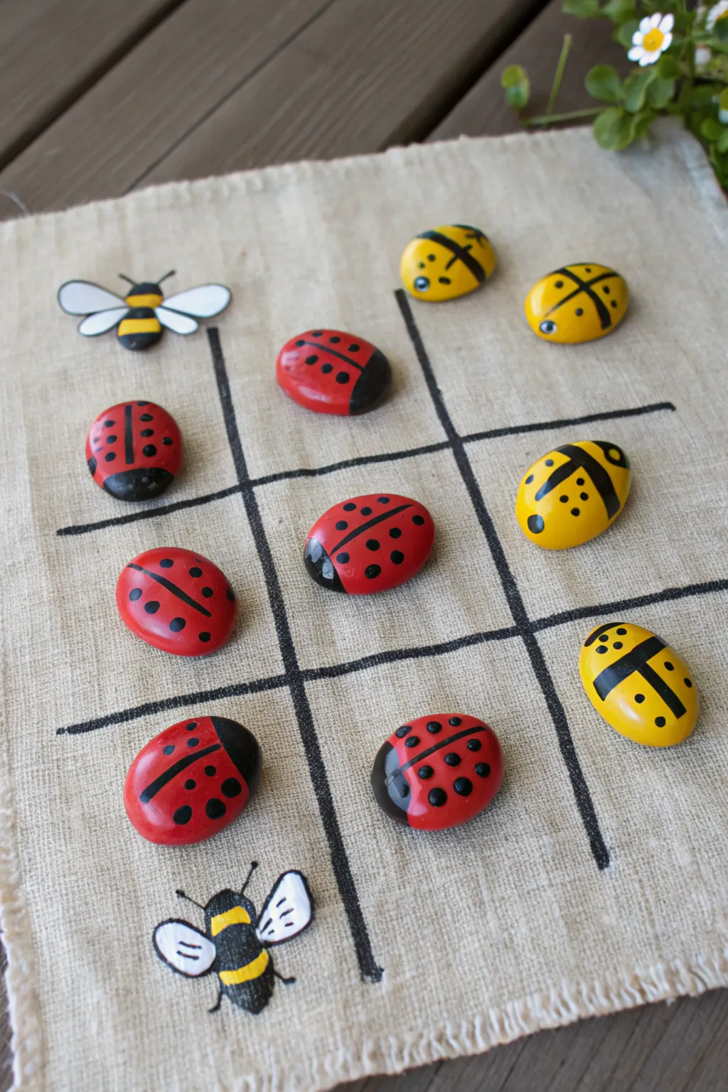 Playful tic-tac-toe painted rock set with ladybugs and bees on a minimal Scandinavian craft table