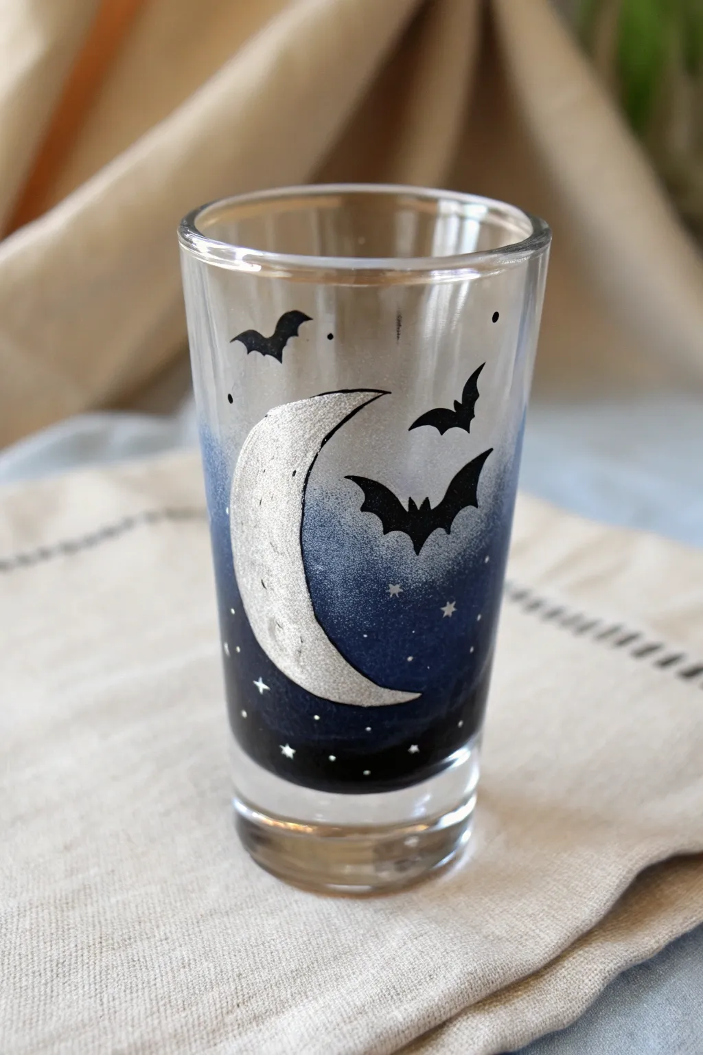 Moody Halloween shot glass paint idea with crescent moon, bats, and midnight ombré glow