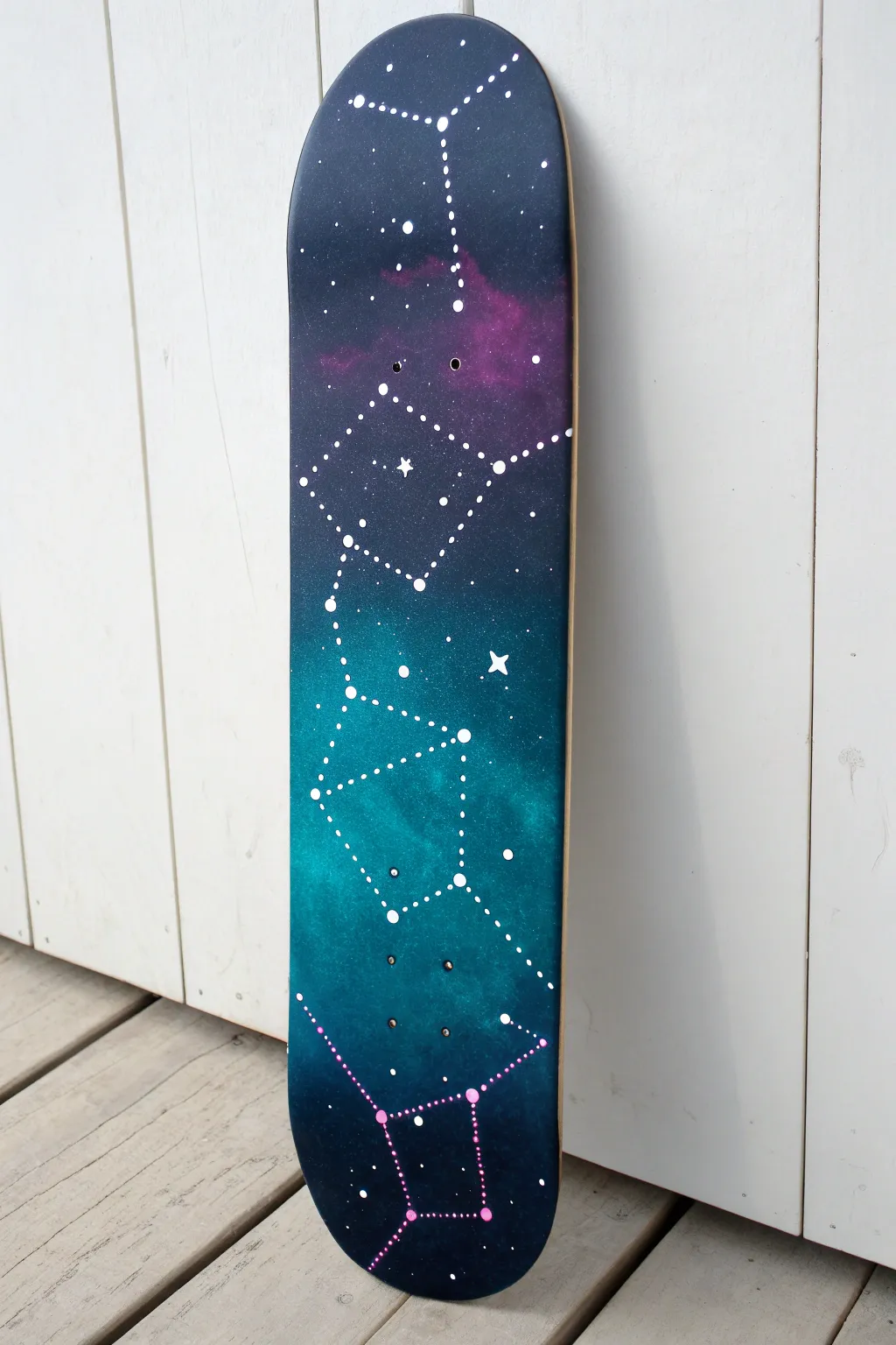 Deep night-sky skateboard deck with glow-in-the-dark constellations, minimalist and wall-ready