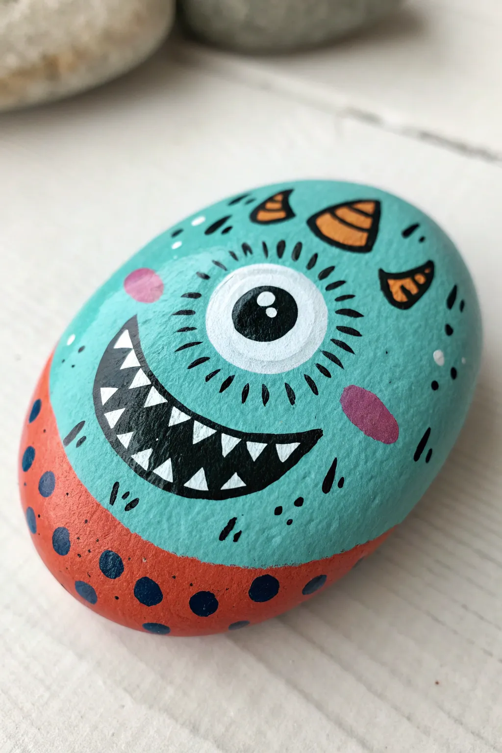 Playful monster face stone in bold colors and dotted texture, perfect for easy rock painting fun