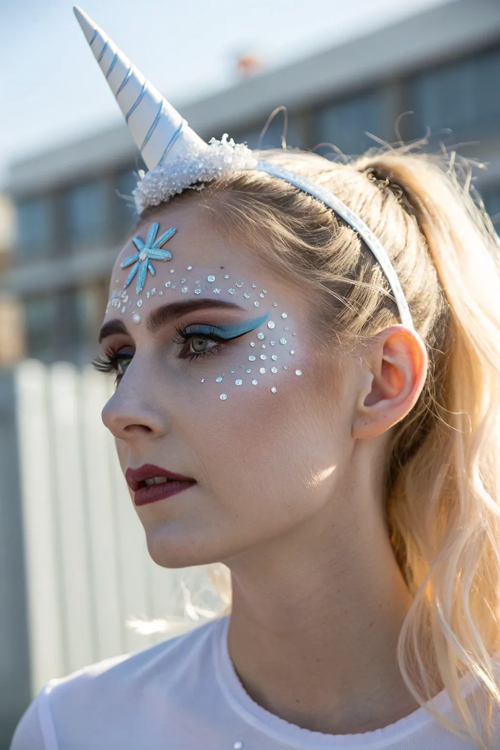 Frosted unicorn face paint with icy horn, pale blue mane accents, and snowflake temples