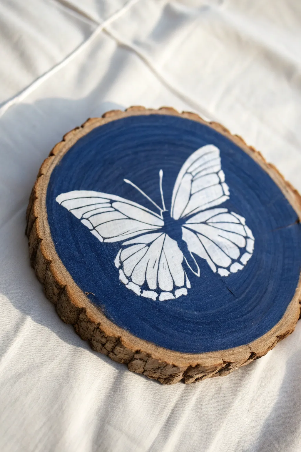Deep indigo wood slice with bare-wood butterfly negative space, clean lines, high-contrast boho minimal.