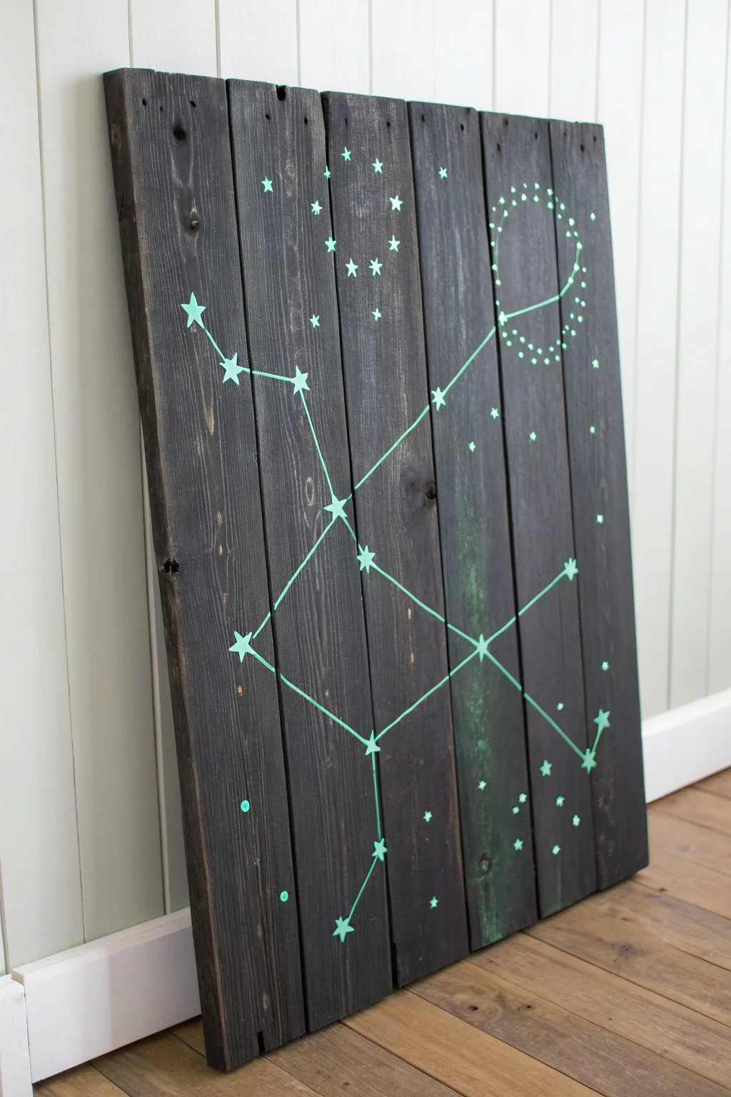 Glow-in-the-dark constellation pallet panel, bold stars on charcoal wood for minimalist boho nights