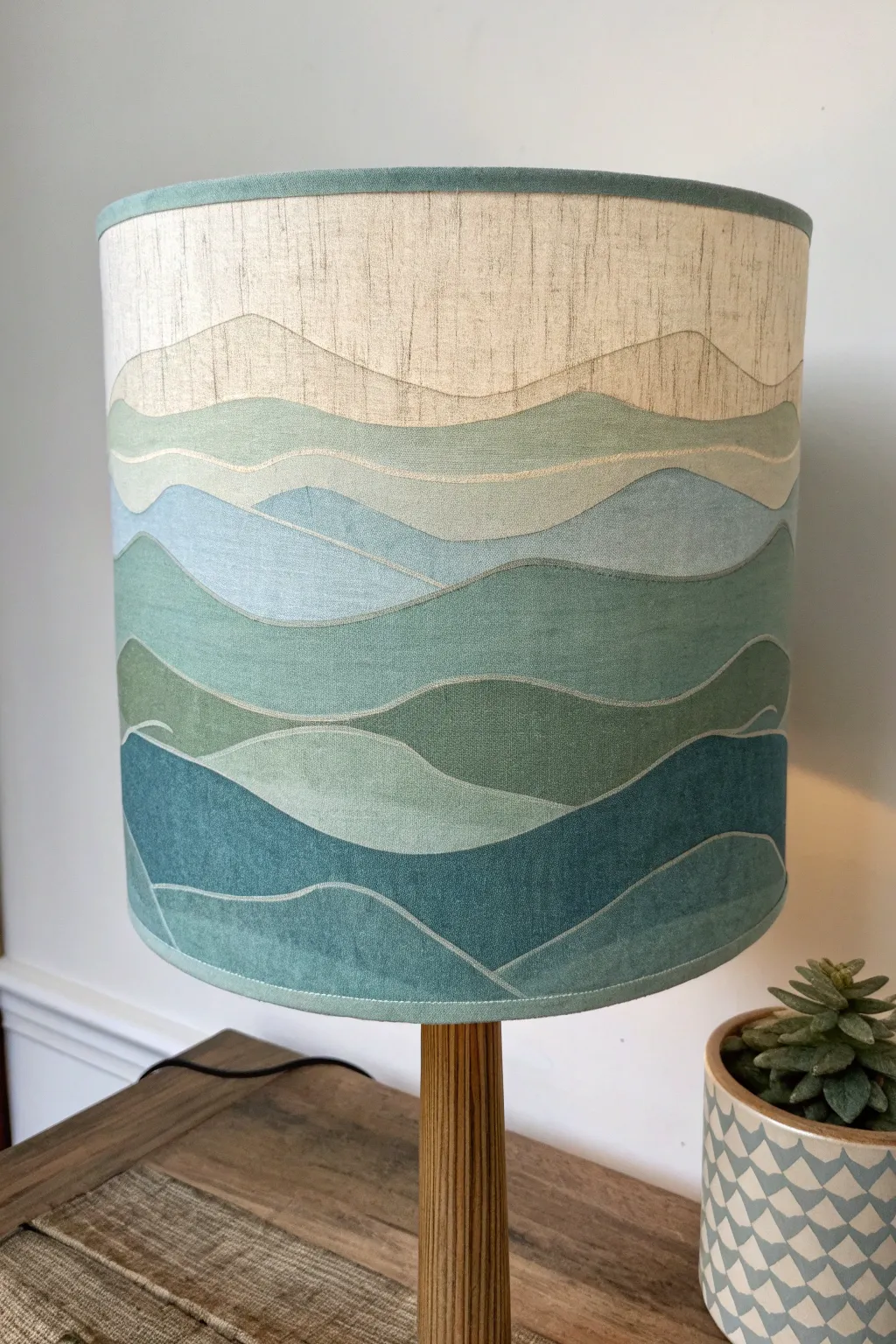 Layered mountain horizons wrap this lampshade in muted tones for a calm Nordic boho glow.