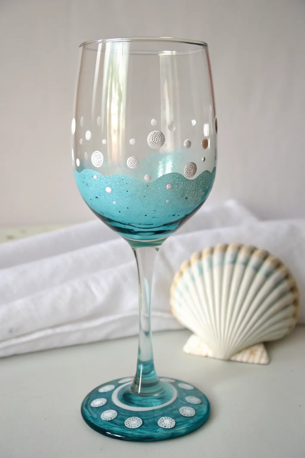 Paint an easy under-the-sea wine glass with bubbles, shells, and a soft blue base wash