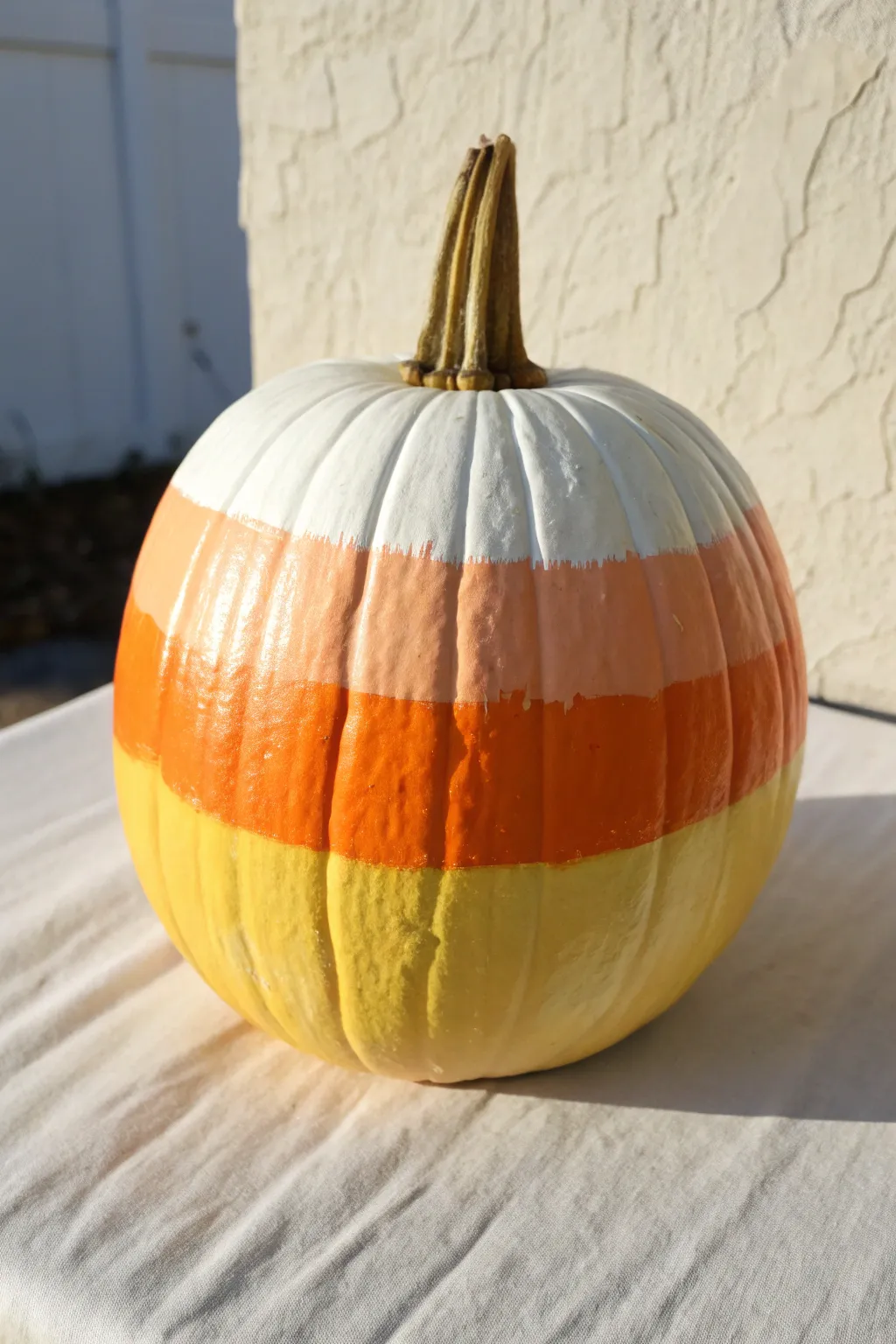 Pastel candy corn pumpkin in bright natural light, minimalist and sweet fall painting inspo