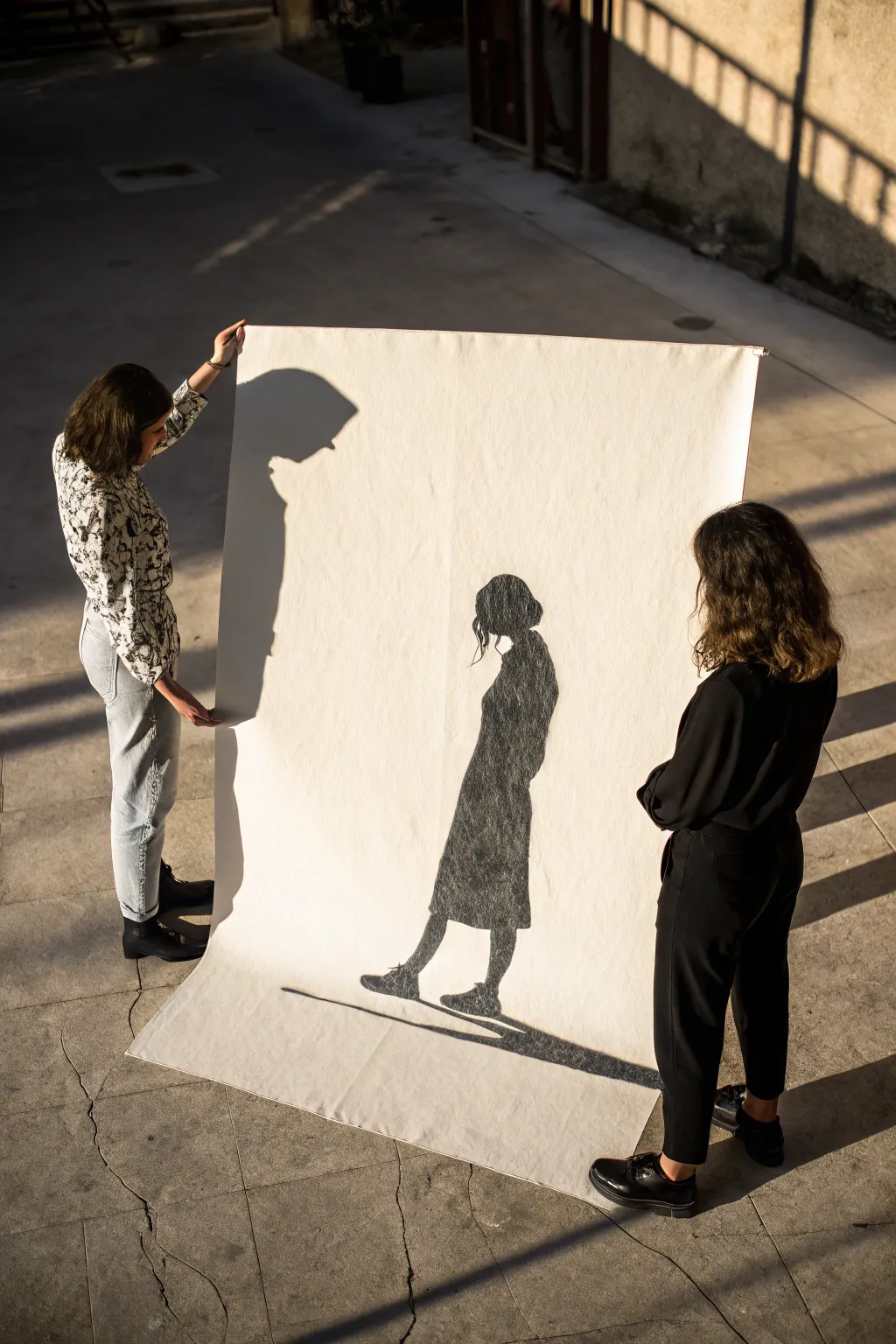 Two figures stand apart while one shared shadow unites them, a minimalist connection sketch.