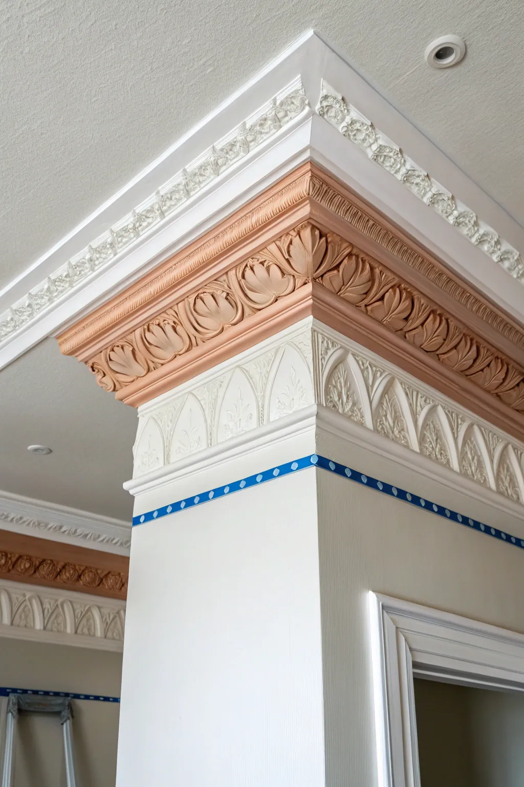 Two-tone crown molding close-up: creamy white with clay accent and painter tape for easy DIY.