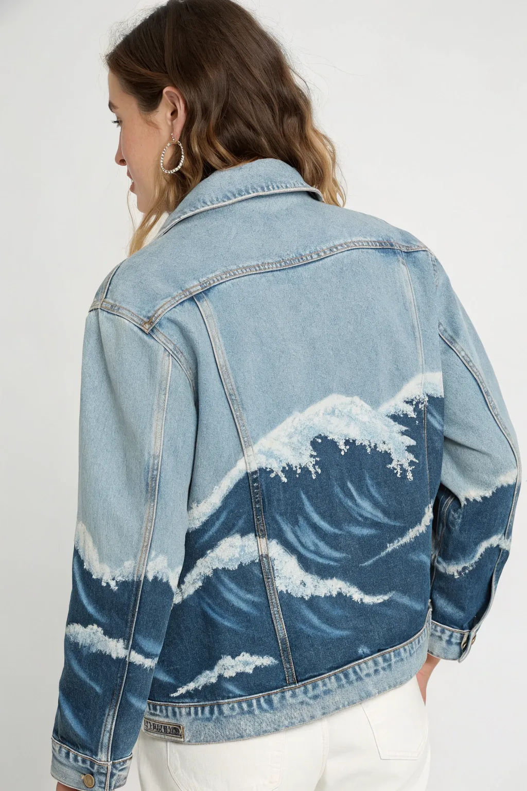Hand-painted denim jacket back with rolling blue waves and crisp foamy highlights in motion
