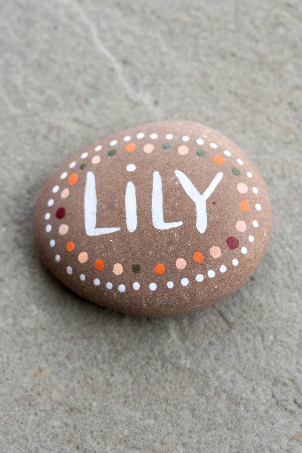 Step-by-step dot-filled name rock, minimalist boho palette on a smooth river stone.