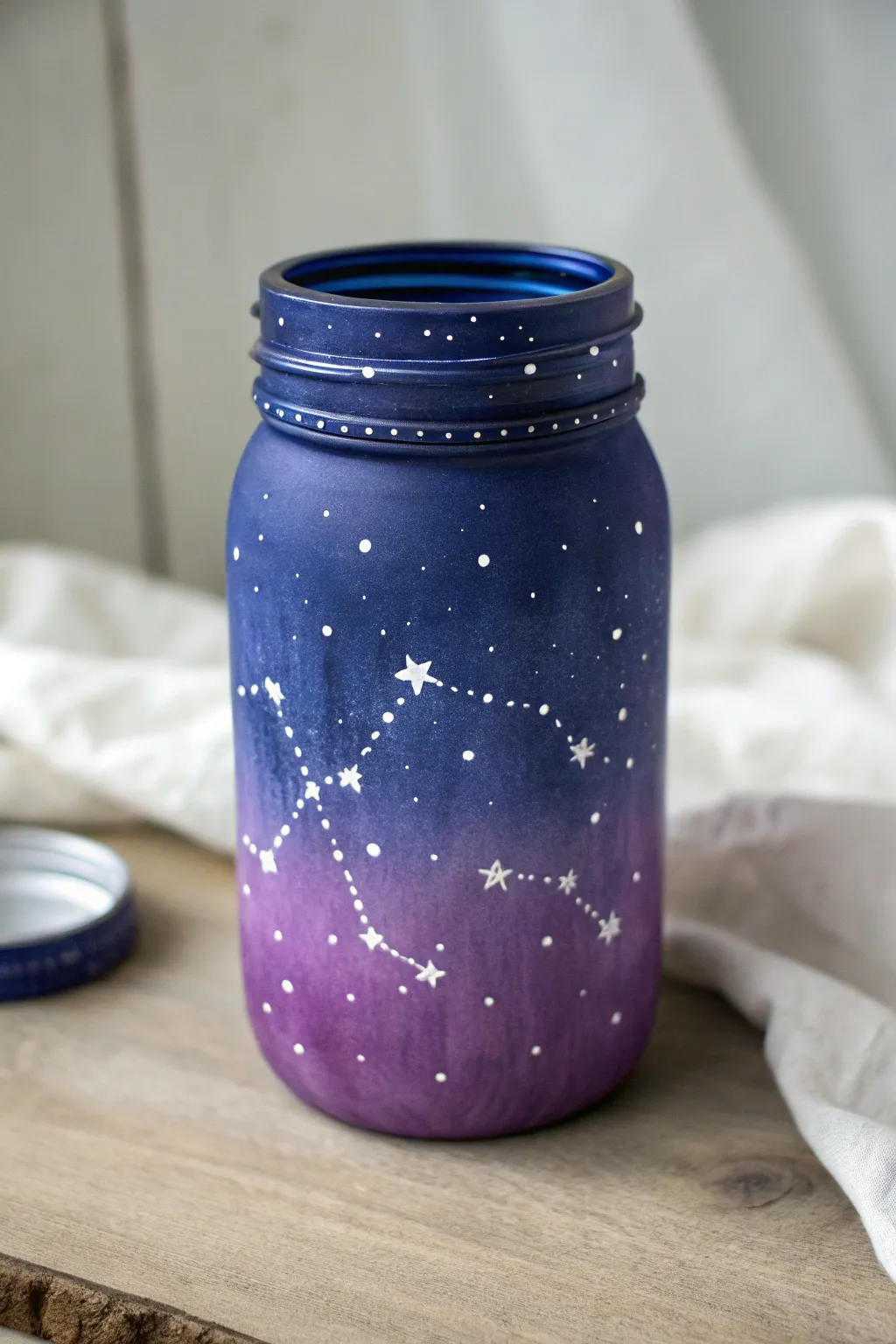 Paint a glowing galaxy mason jar with star splatter and tiny constellations in moody light