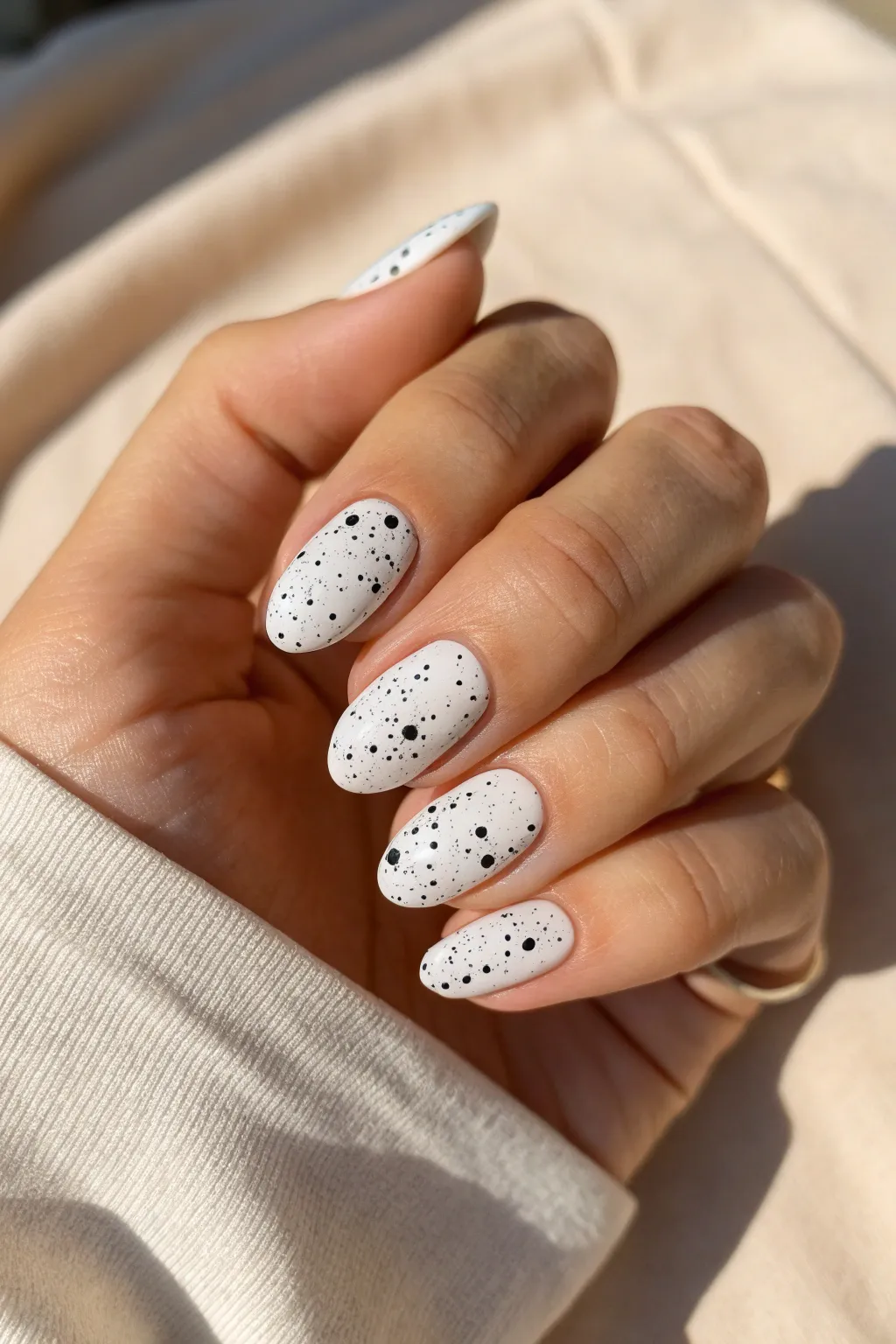 Dalmatian dot nails: a clean nude base with inky black speckles for modern minimal charm