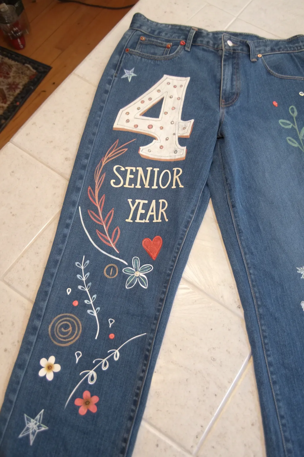 Senior-year celebration jeans with a bold year number and sweet icons in clean boho minimal style.