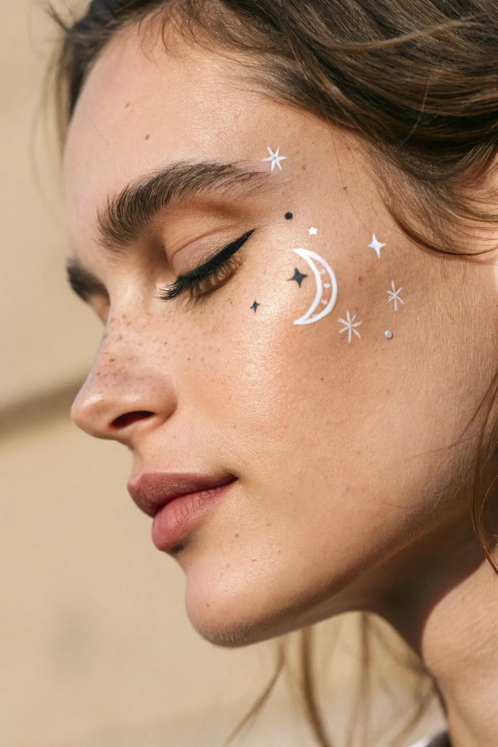 Delicate crescent moon face paint with tiny stars and soft sparkles for an easy dreamy look