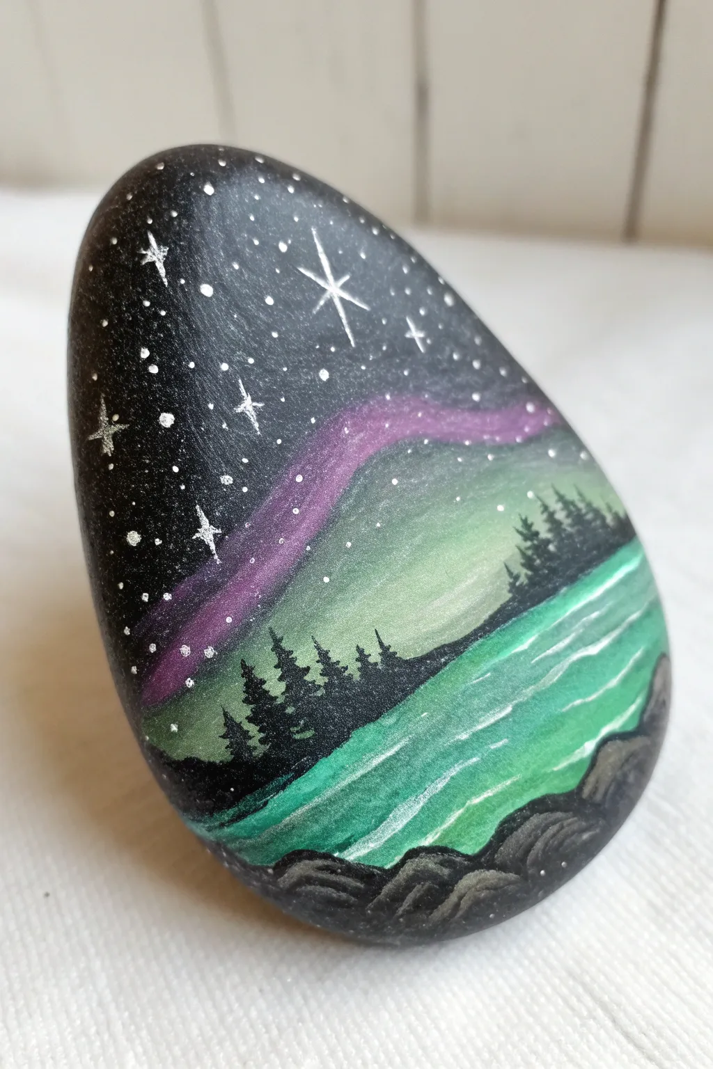 Aurora rock painting in emerald and violet over a frosty lake horizon, calm minimalist winter vibes