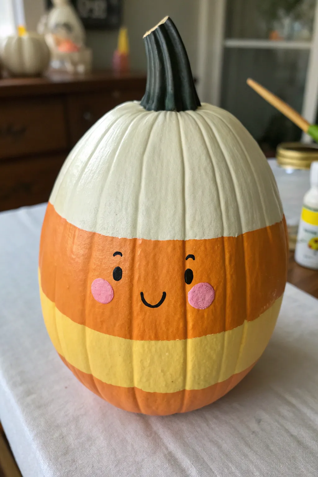Candy corn pumpkin with a sweet smiley face, minimal stripes, soft blush cheeks, cozy contrast