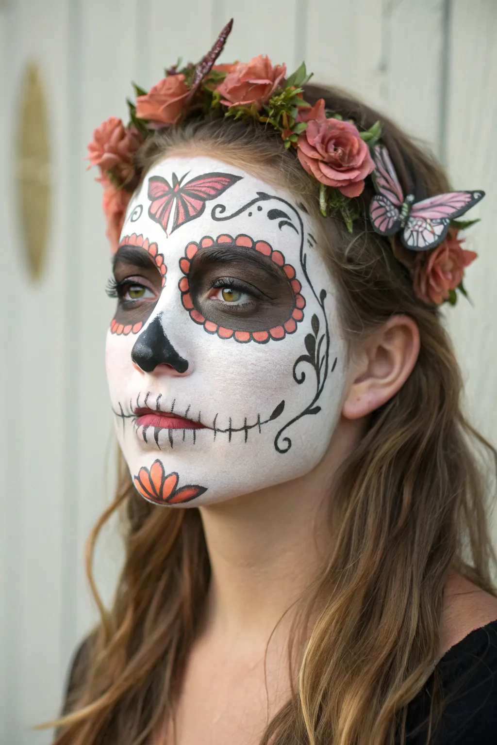 Butterfly accents meet a classic sugar skull base for a soft, boho Día de los Muertos look