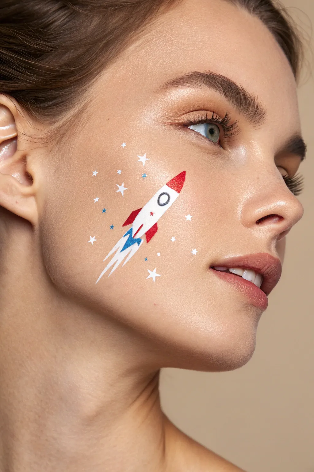 Retro cheek rocket with a red white and blue sparkly trail, playful Fourth of July face paint.