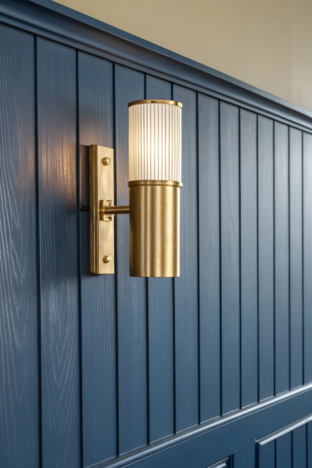 Elevate your space with brass sconces on moody navy wainscoting for a cozy finish.