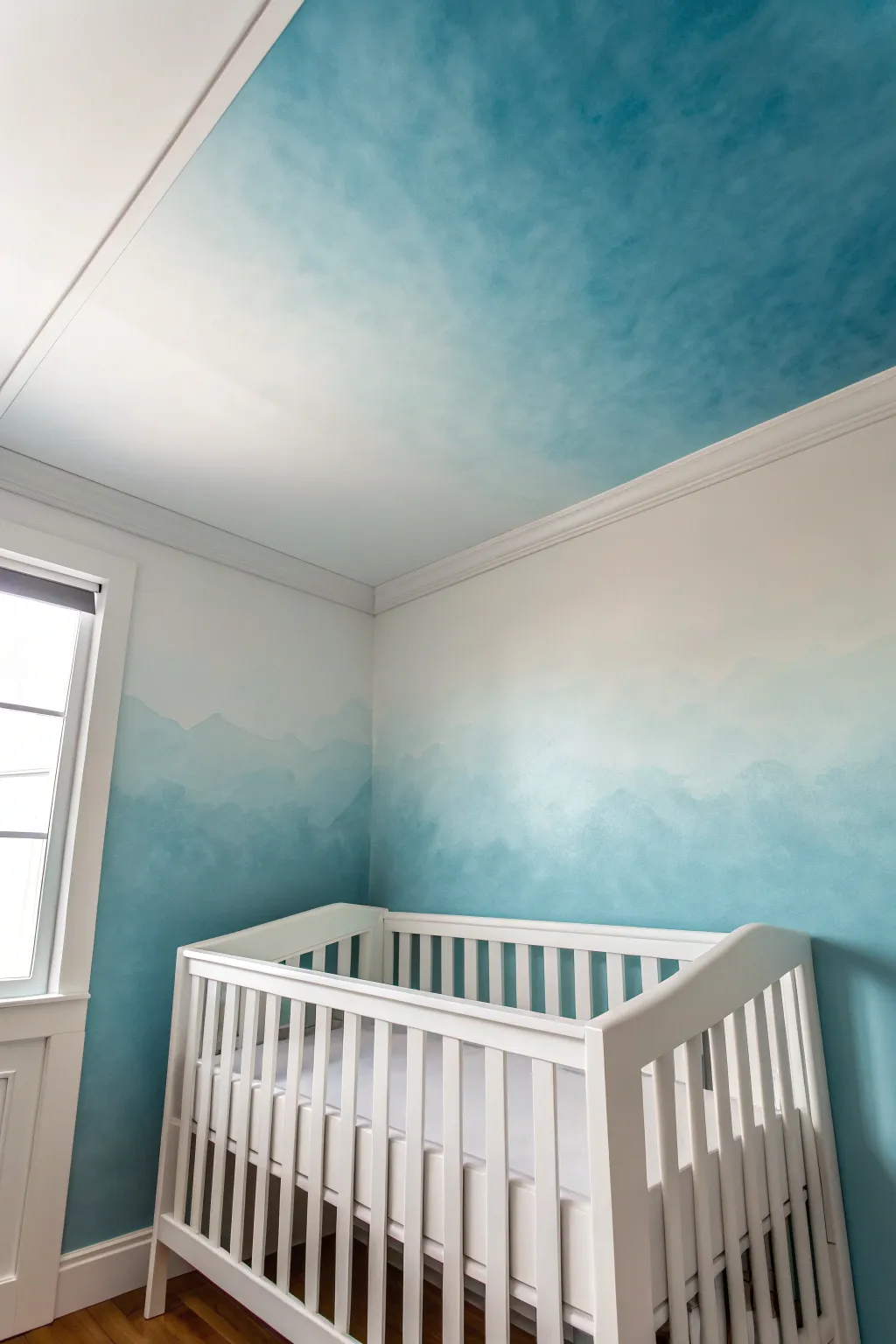 Soft ombre wall-to-ceiling sky fade makes the nursery feel airy, calm, and cocooning.