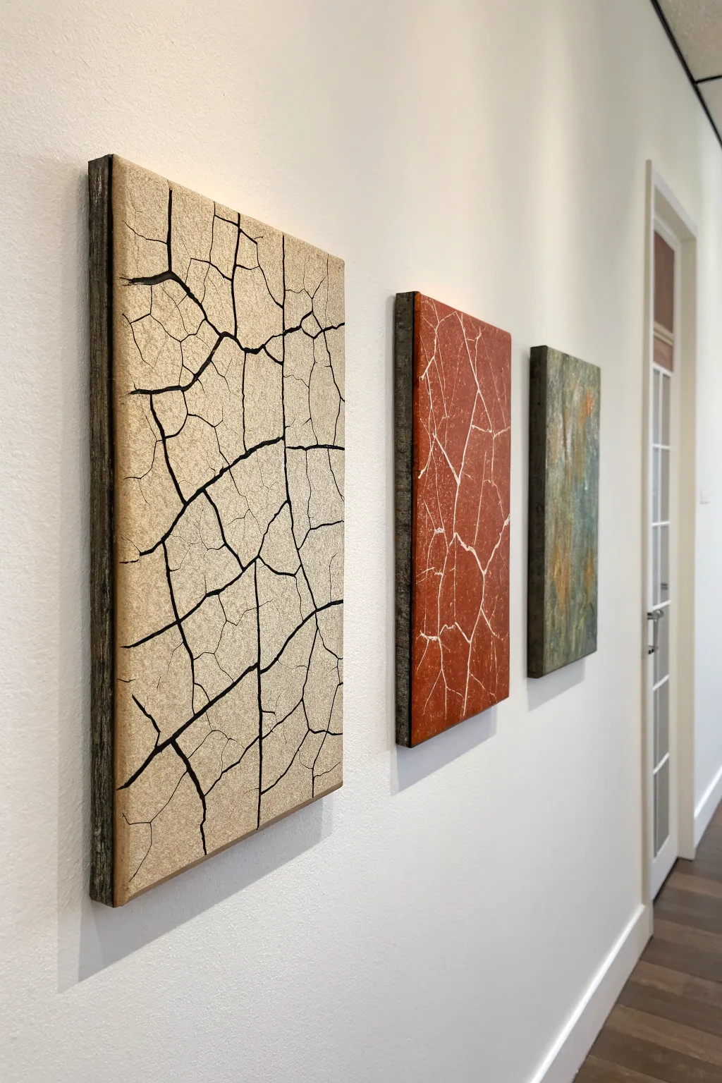 Minimalist crackle art triptych with layered earthy tones and bold shapes in soft daylight