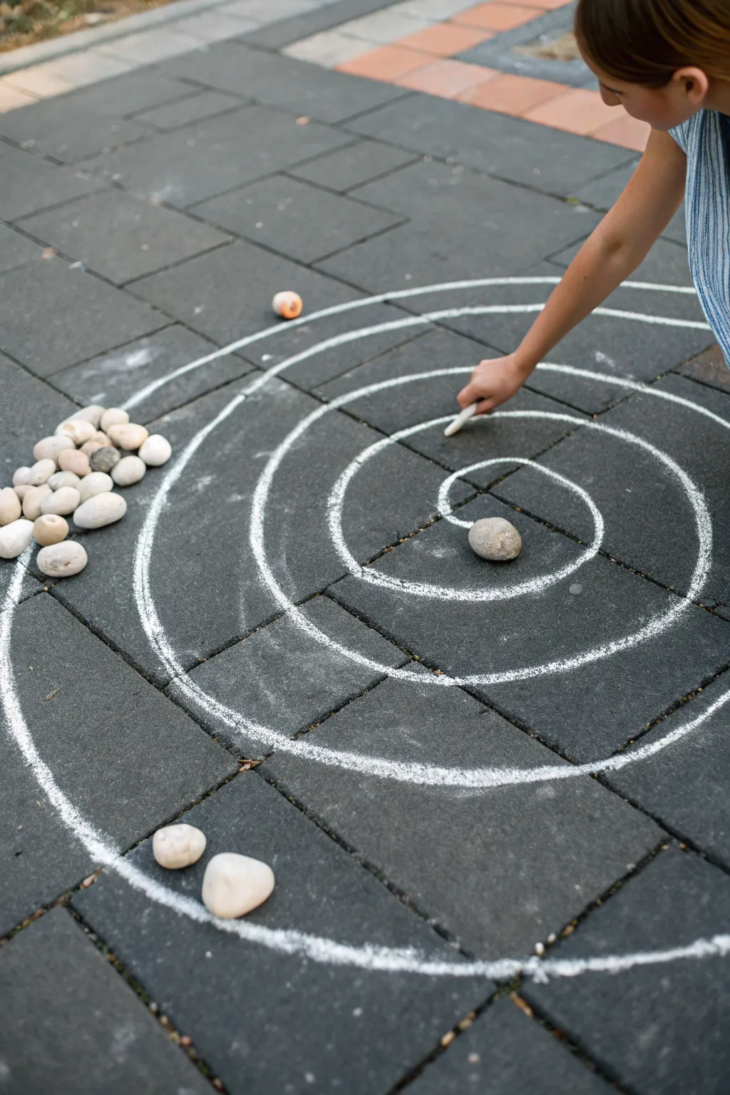 Minimal chalk target rings with toss stones and a pointing hand for easy toss-and-score play