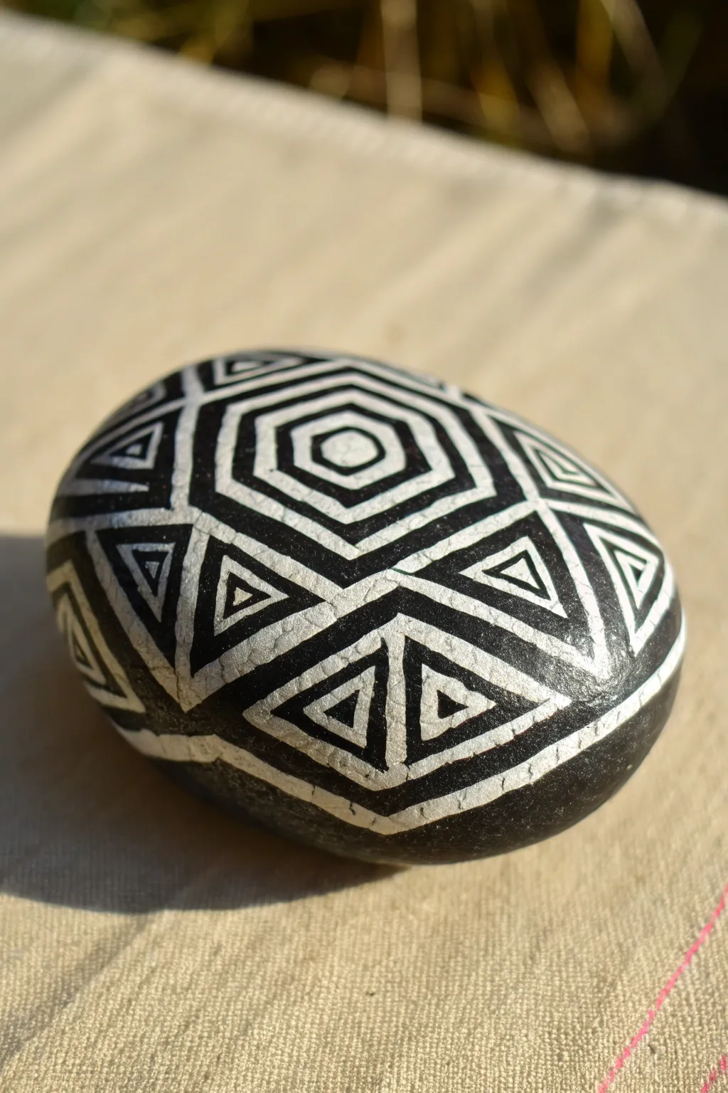 Black-and-white geometric rock with a 3D cube illusion, side-lit for dramatic contrast