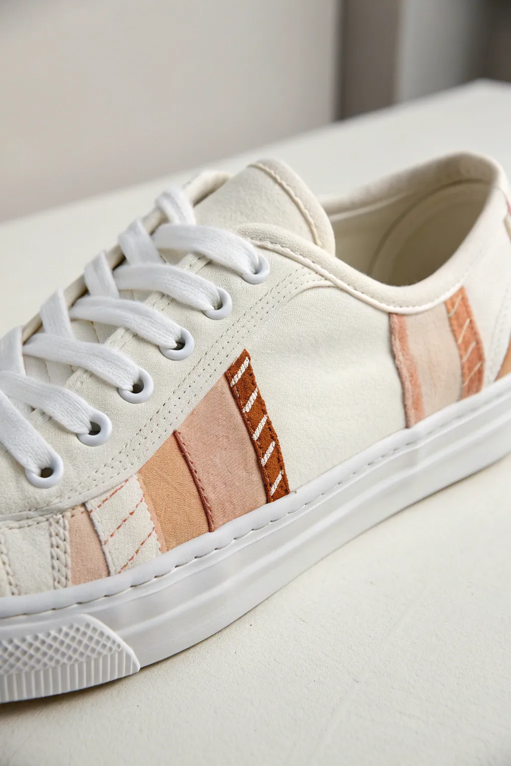 Mixed-media sneaker collage with stitched fabric patches and soft paint blending in neutral tones