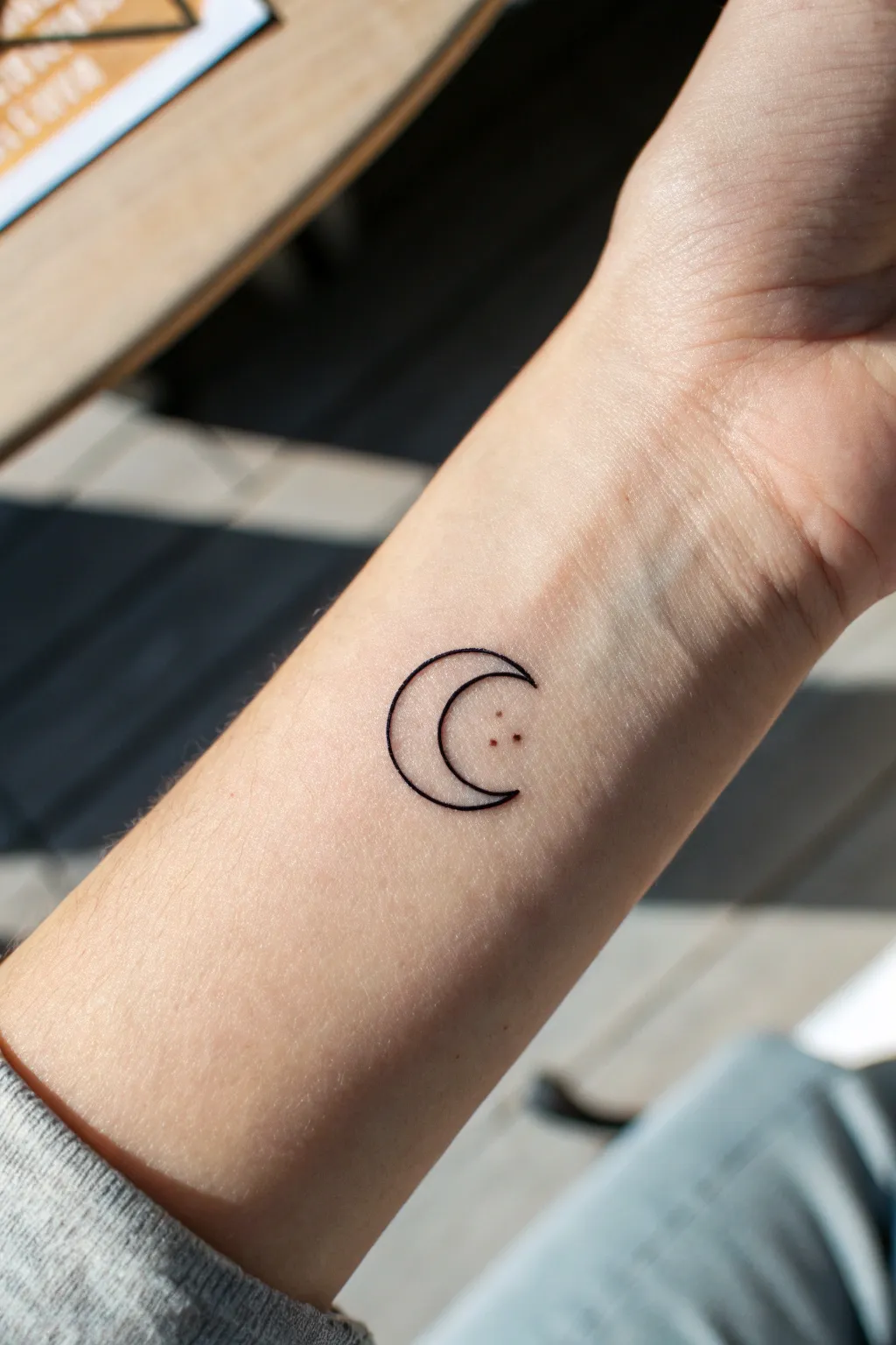 Negative space mini symbol tattoo with crisp black ink and a clever cutout detail in sharp focus.