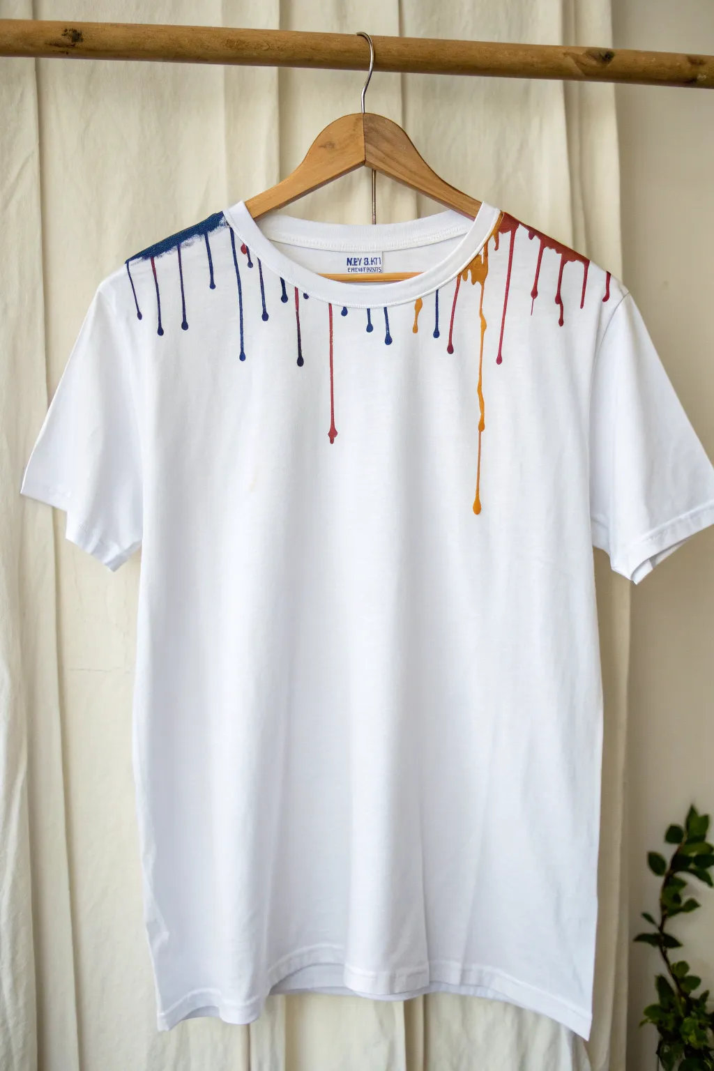 Collar-to-midshirt drip art on a crisp white tee, bold color runs with clean minimalist contrast.