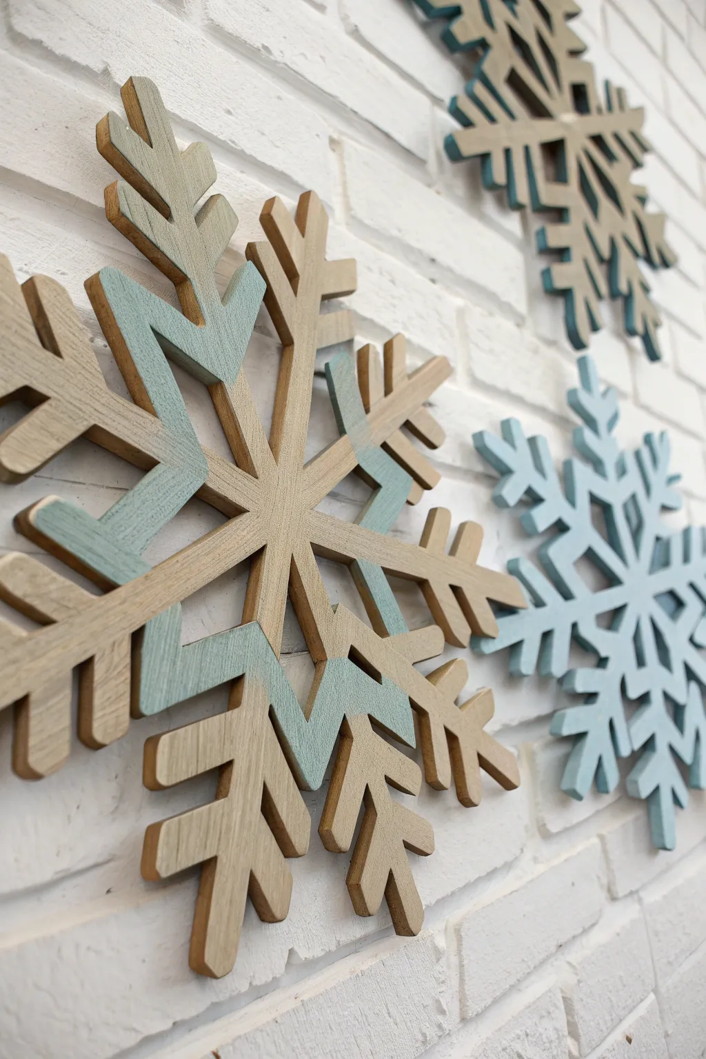 Layered painted wooden snowflakes in coordinated winter hues, minimalist wall art with depth