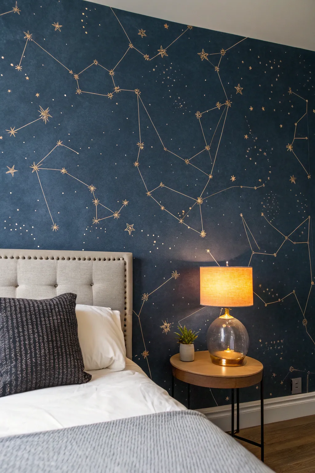 Moody night-sky wall: hand-painted constellations in deep navy, warmed by a soft lamp glow.