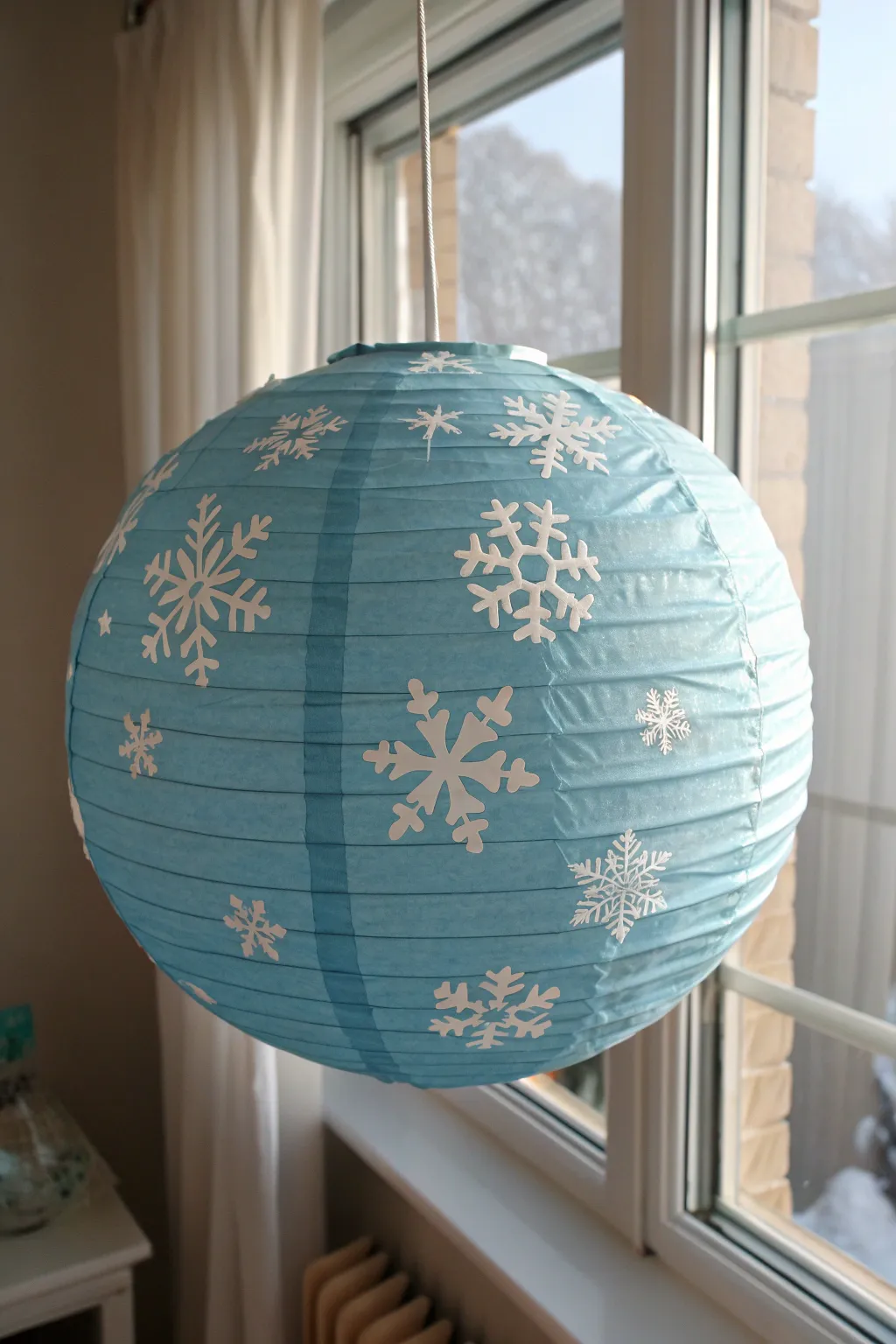 Paint icy blue and scatter snowy whites for a crisp winter lantern glow by the window.